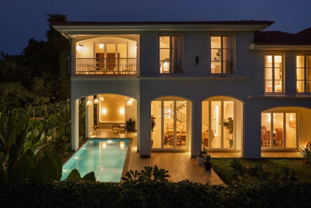 Luxury villa exterior at night featuring illuminated interiors and a private swimming pool by Isprava.